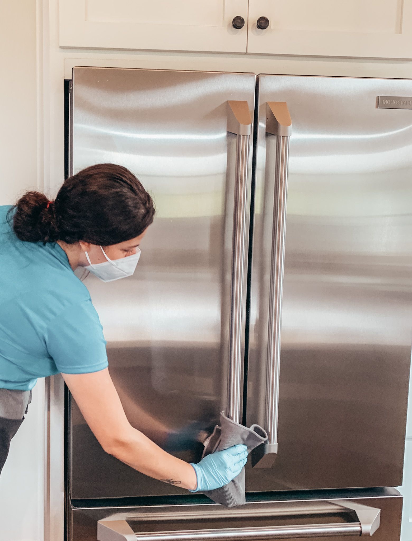 Merry Maids® professional cleaning the outside of a stainless steel fridge