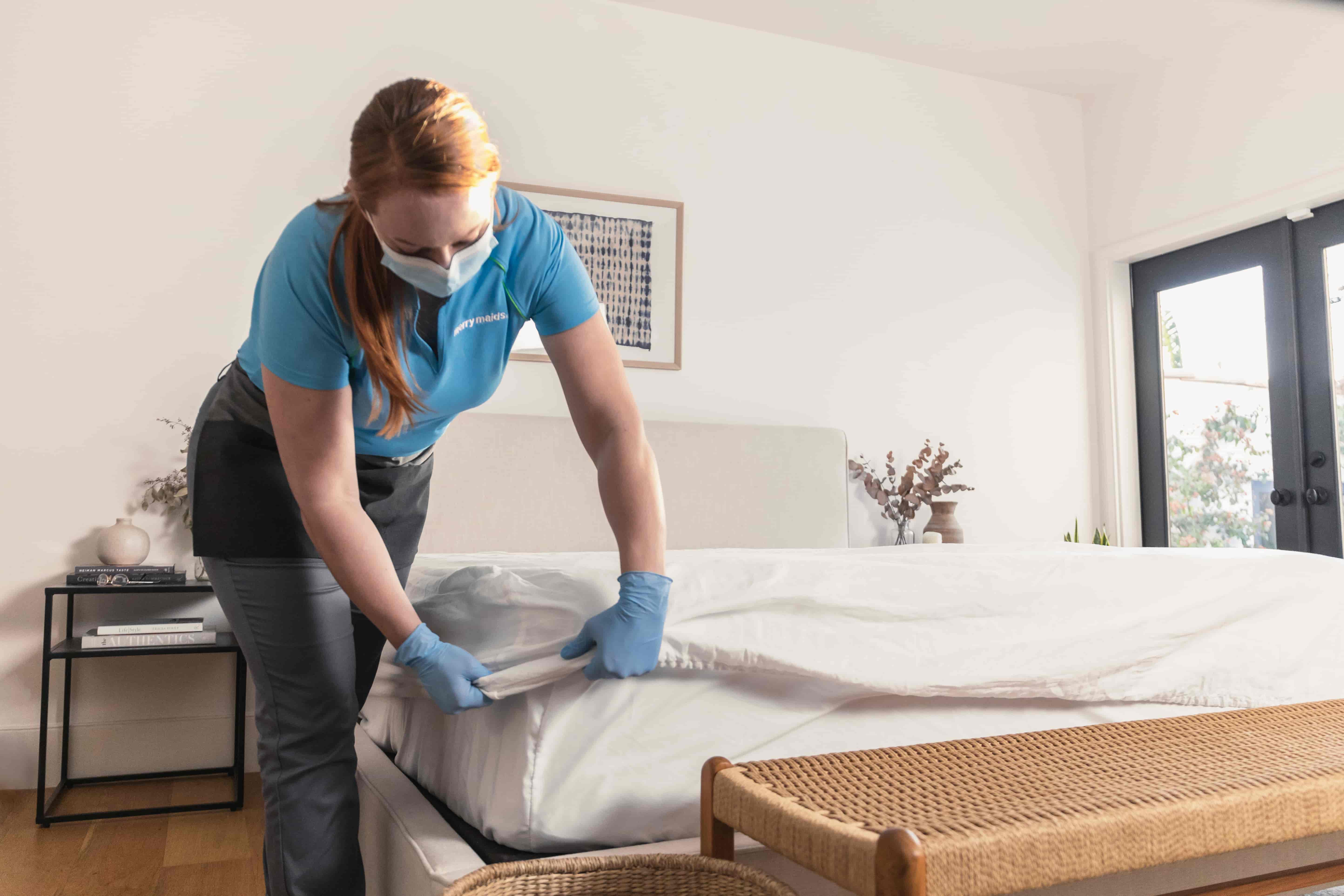 Professional house cleaner making bed