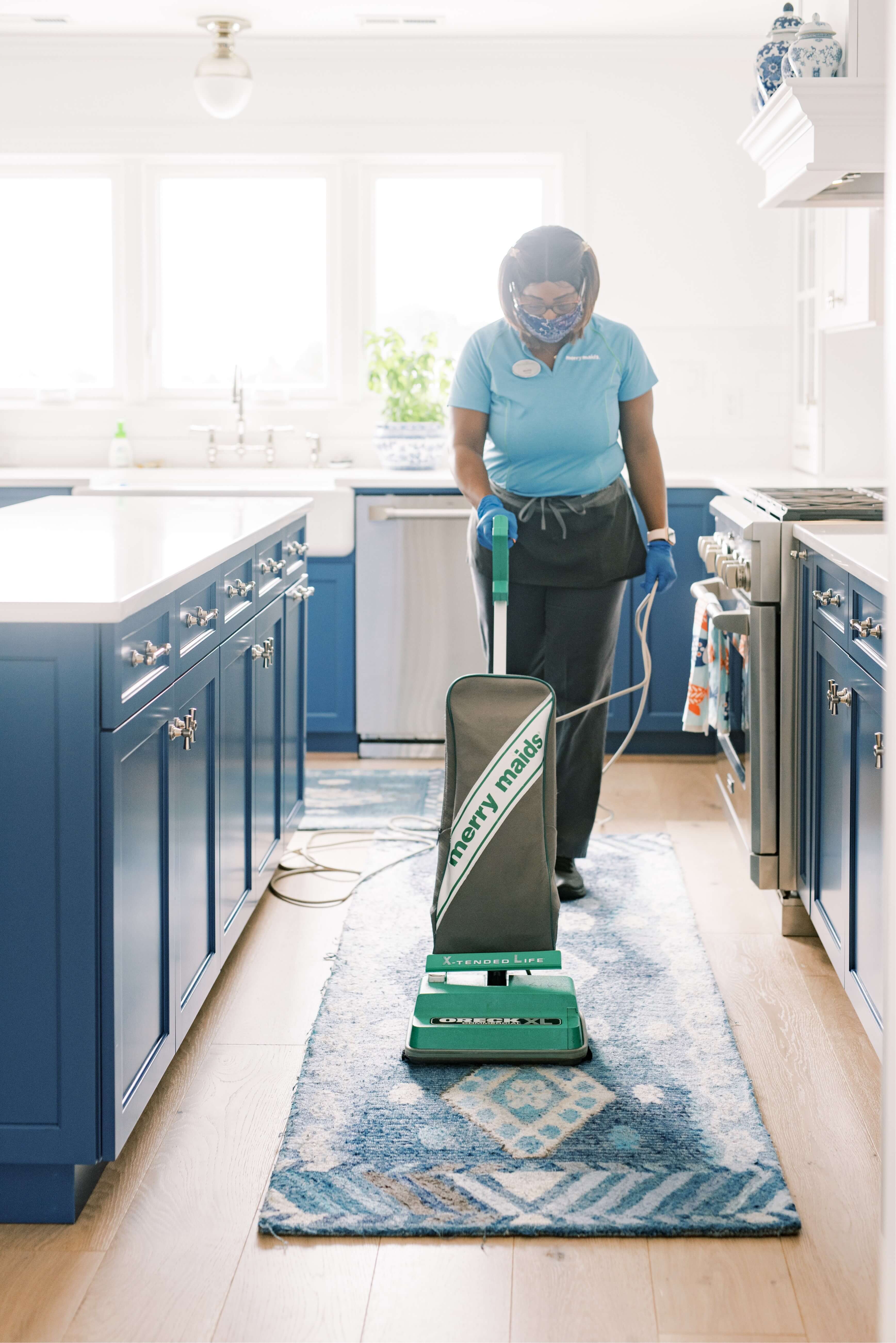 Merry Maids team member vacuuming in kitchen